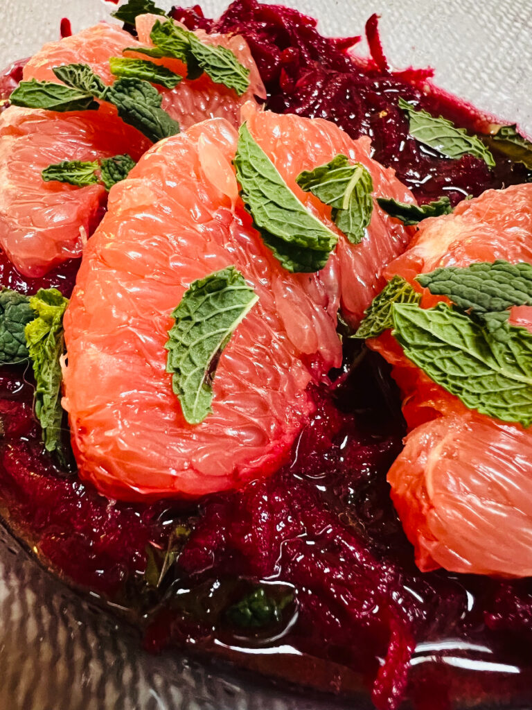 Bright raw beet salad topped with grapefruit sections and mint